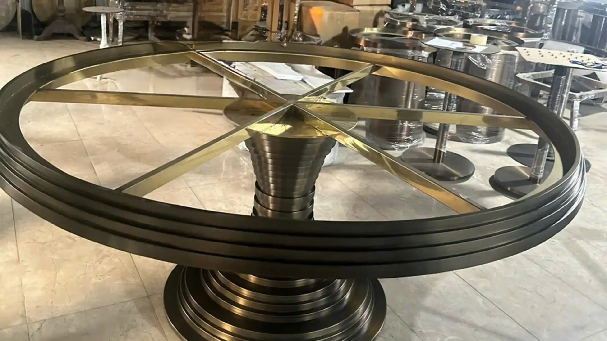 Large circular metal table base structure prepared for PVD coating, featuring intricate brass and dark metal components.