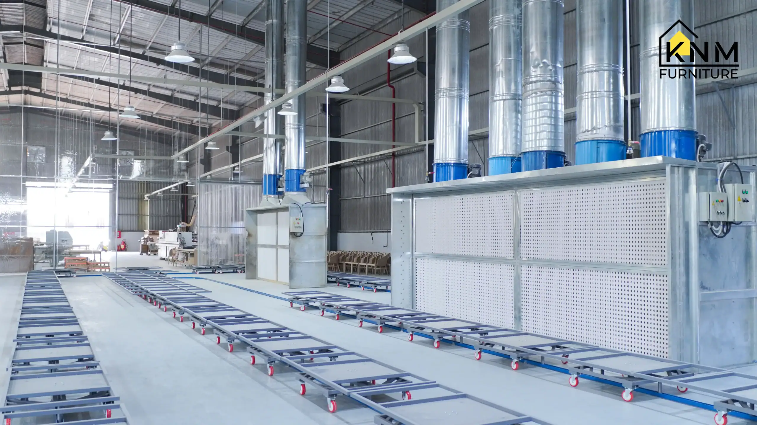 Advanced, industrial-grade pressurized spray booth system at Khanom Furniture Vietnam factory, utilizing an integrated roller conveyor system for precise, dust-free lacquer application on all hospitality furniture components.