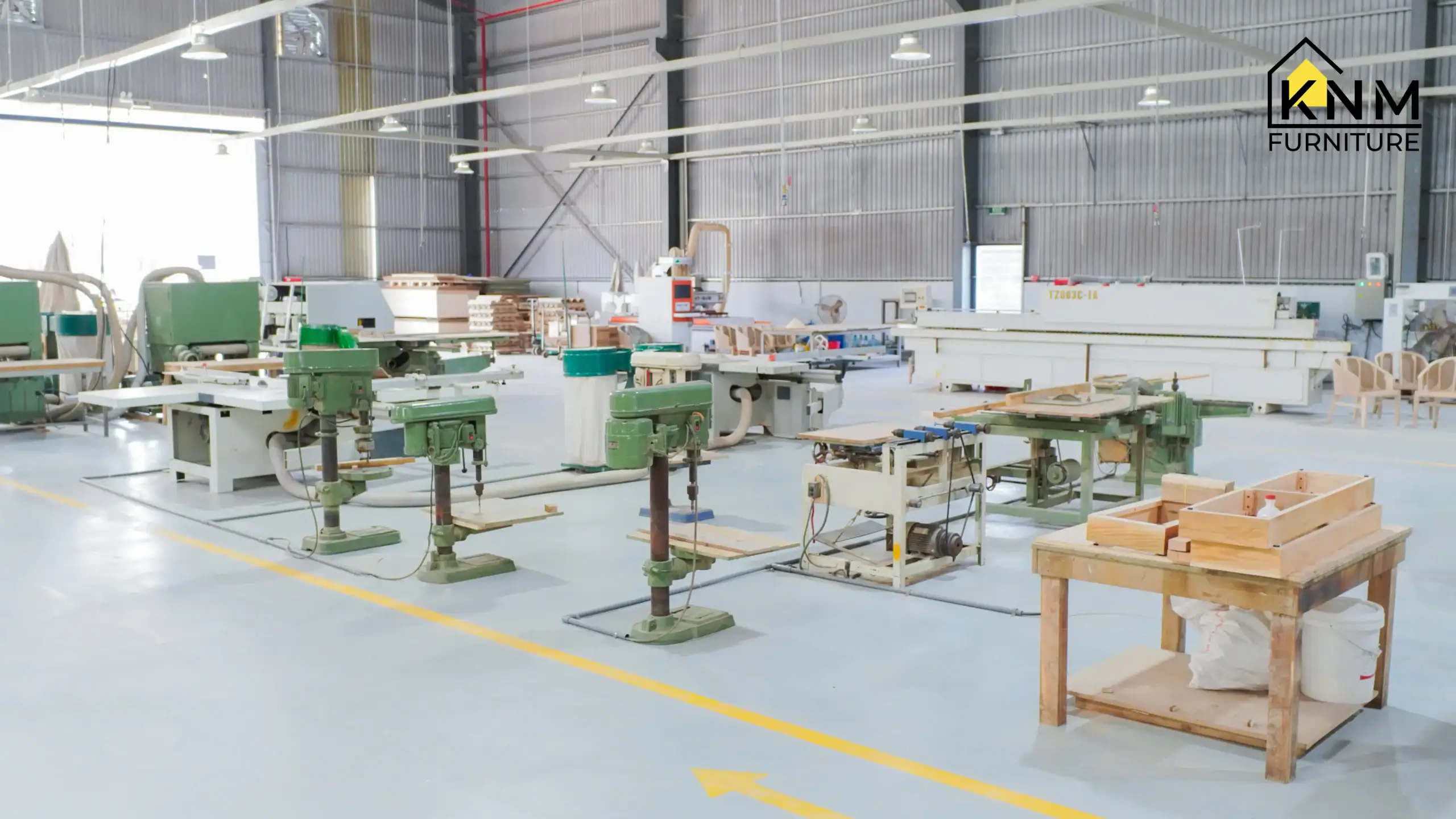 nterior view of the Khanom Furniture Vietnam precision woodworking workshop, showcasing industrial equipment including drill presses and large panel saws, connected to an efficient dust management system for safety and quality.