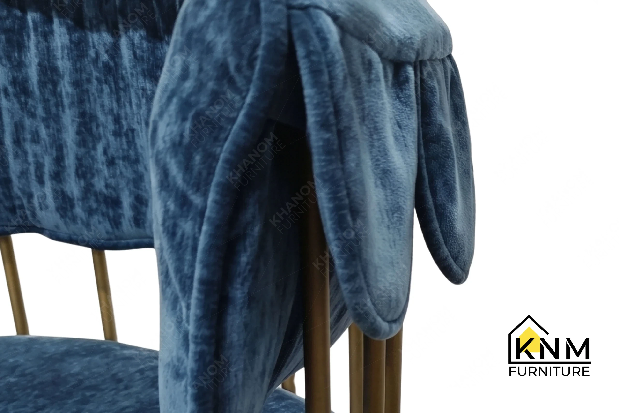 A detailed material zoom of the scalloped brass outdoor dining chair by Khanom Furniture, showing the interaction between the textured fabric and the painted brass cast iron.