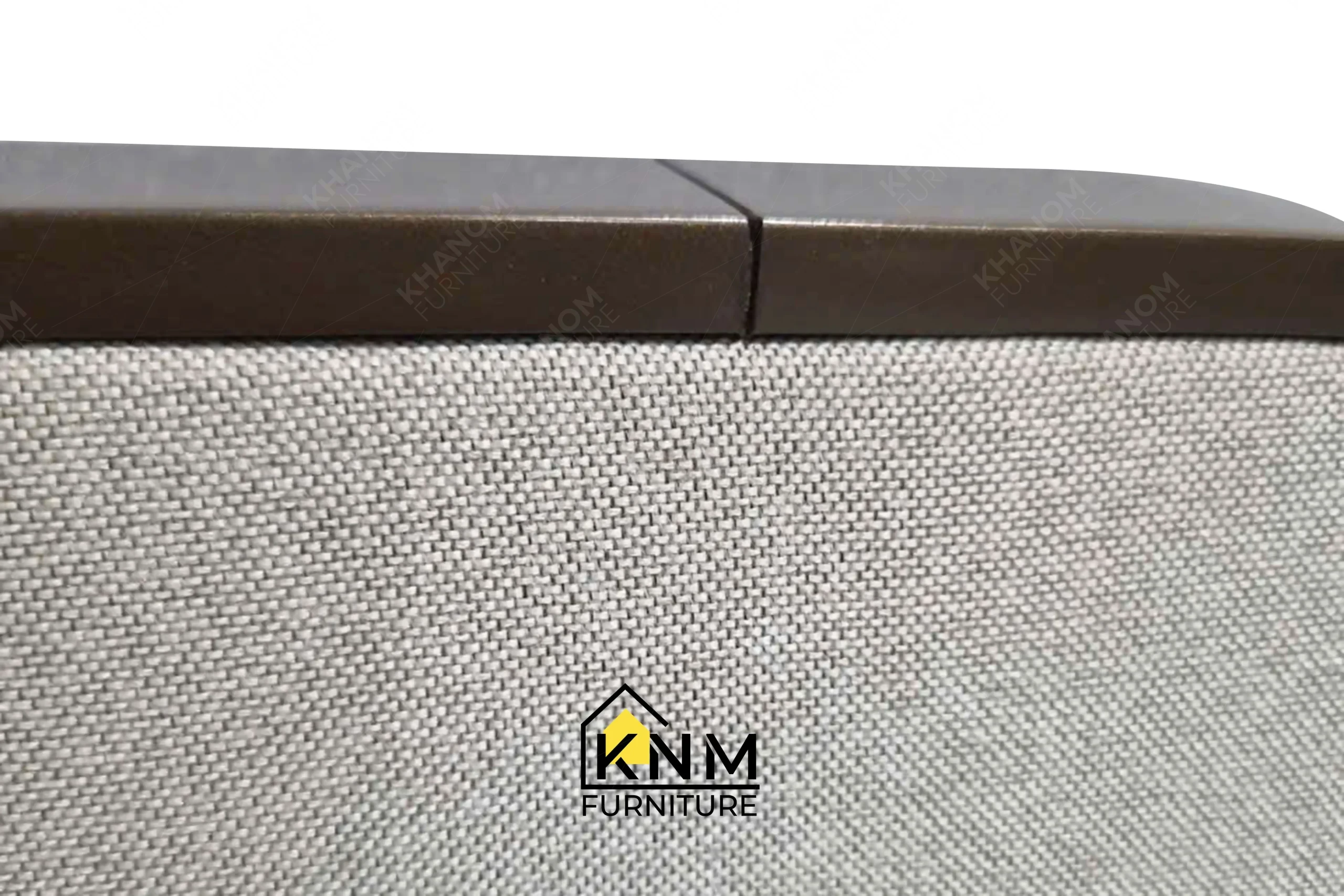 A detailed material zoom of the bronze Granex upholstered bed system by Khanom Furniture, showing the fabric texture adjacent to the plated metal.