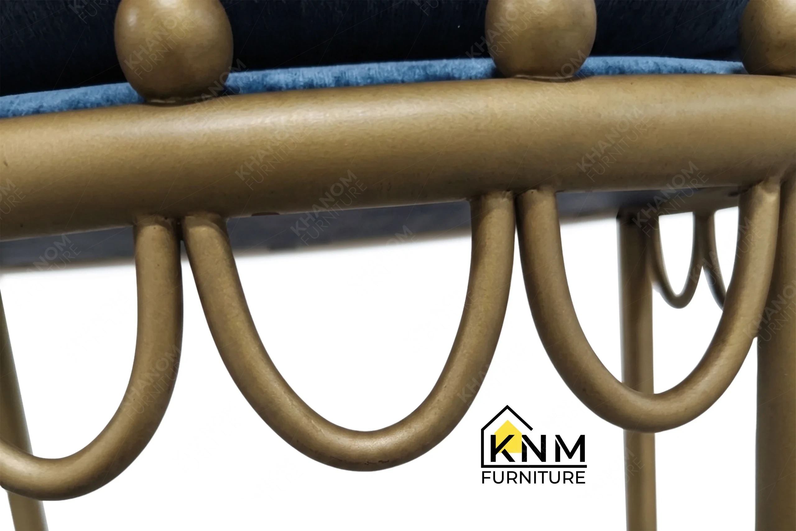 A craftsmanship close-up of the scalloped brass outdoor dining chair from Khanom Furniture, highlighting the secure weld joints and decorative spherical knobs.