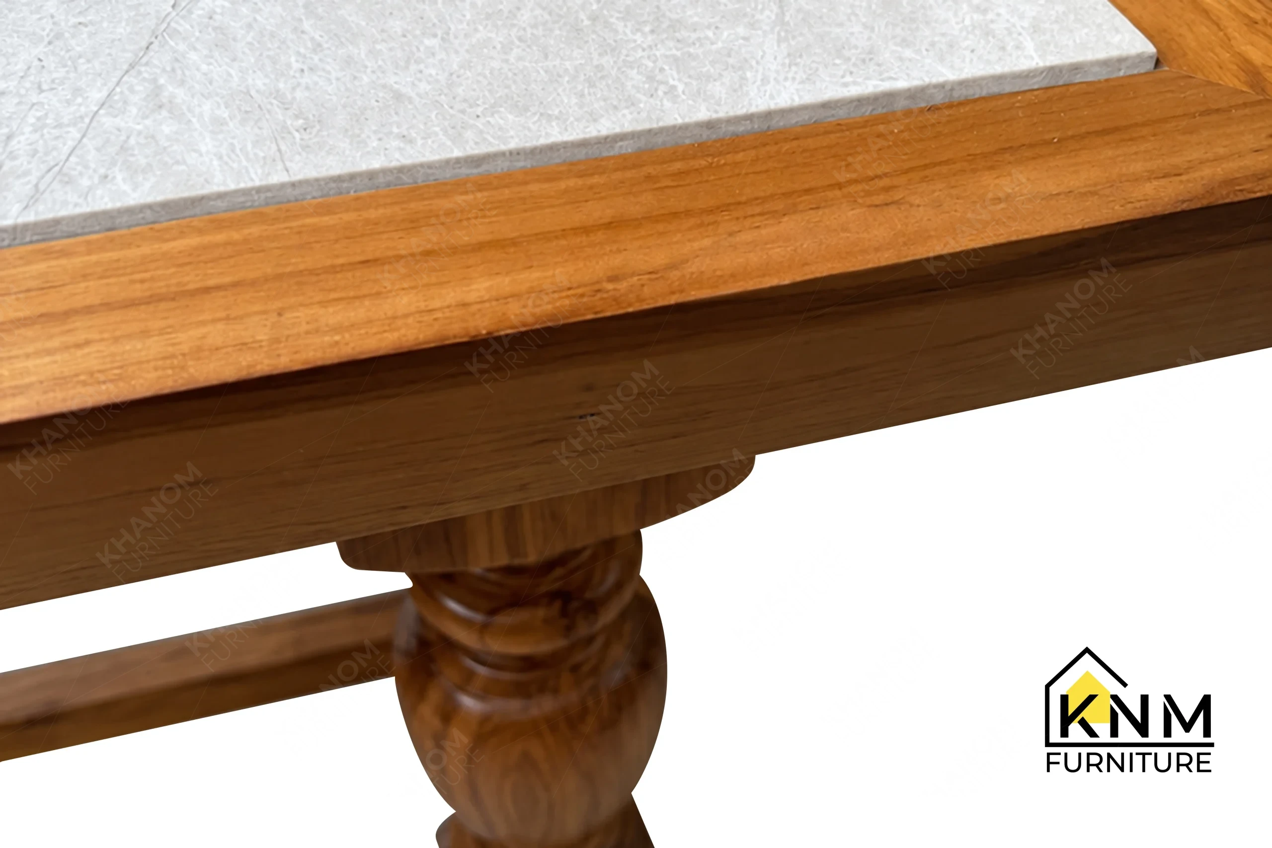 A detailed material zoom of the stone top teak communal table by Khanom Furniture, showing the precision joint between the stone and the teak frame.