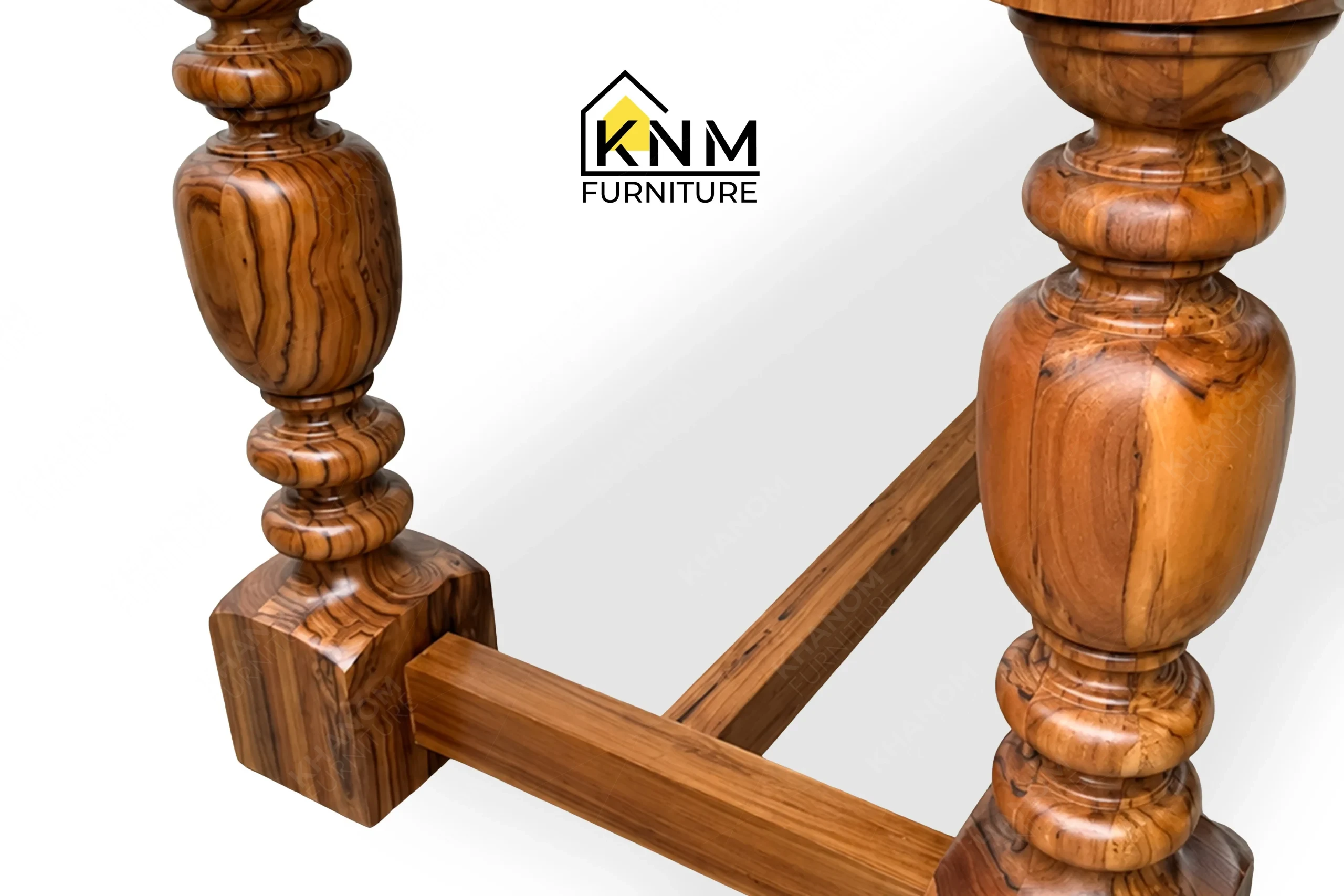 A technical detail of the stone top teak communal table from Khanom Furniture, describing the solid wood turned legs and stretcher joinery.