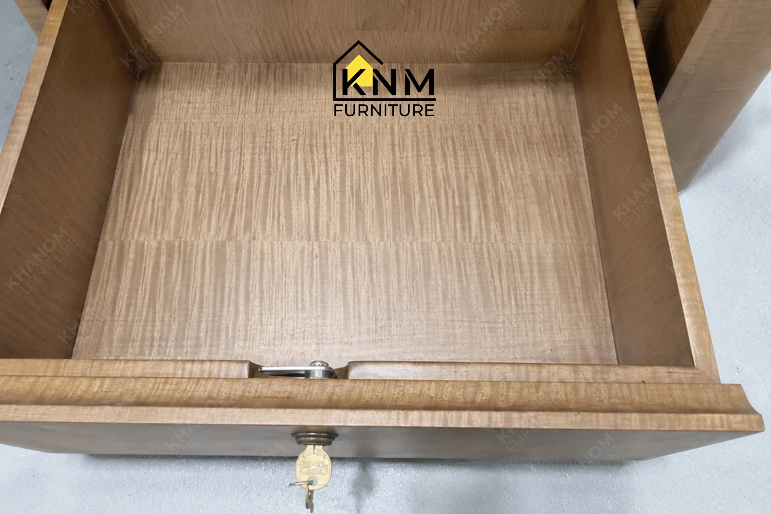 A detailed material zoom of the figured walnut lobby concierge desk by Khanom Furniture, showing the complex quartered grain pattern.