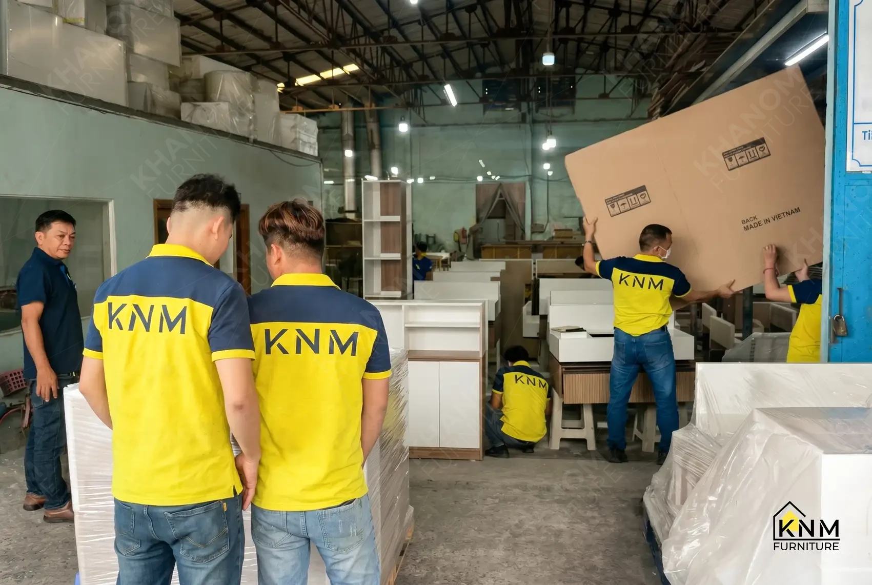 Finished custom cabinets partially wrapped in protective PE film staged in the loading area at Khanom Furniture (KNM Furniture), a custom furniture factory Vietnam.