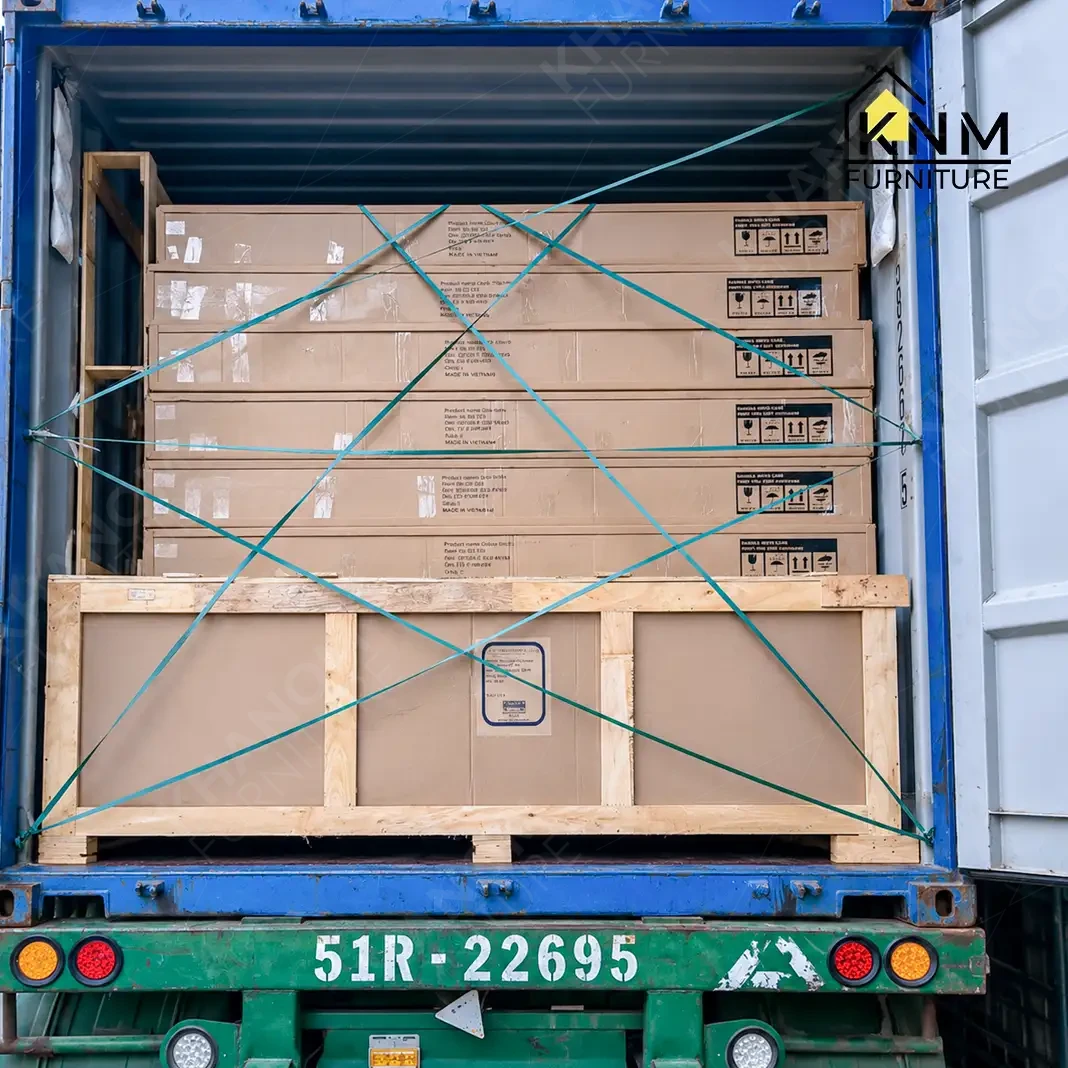 Green X-pattern cargo straps securing furniture cartons on pallet inside container for ocean freight — KNM Furniture Vietnam