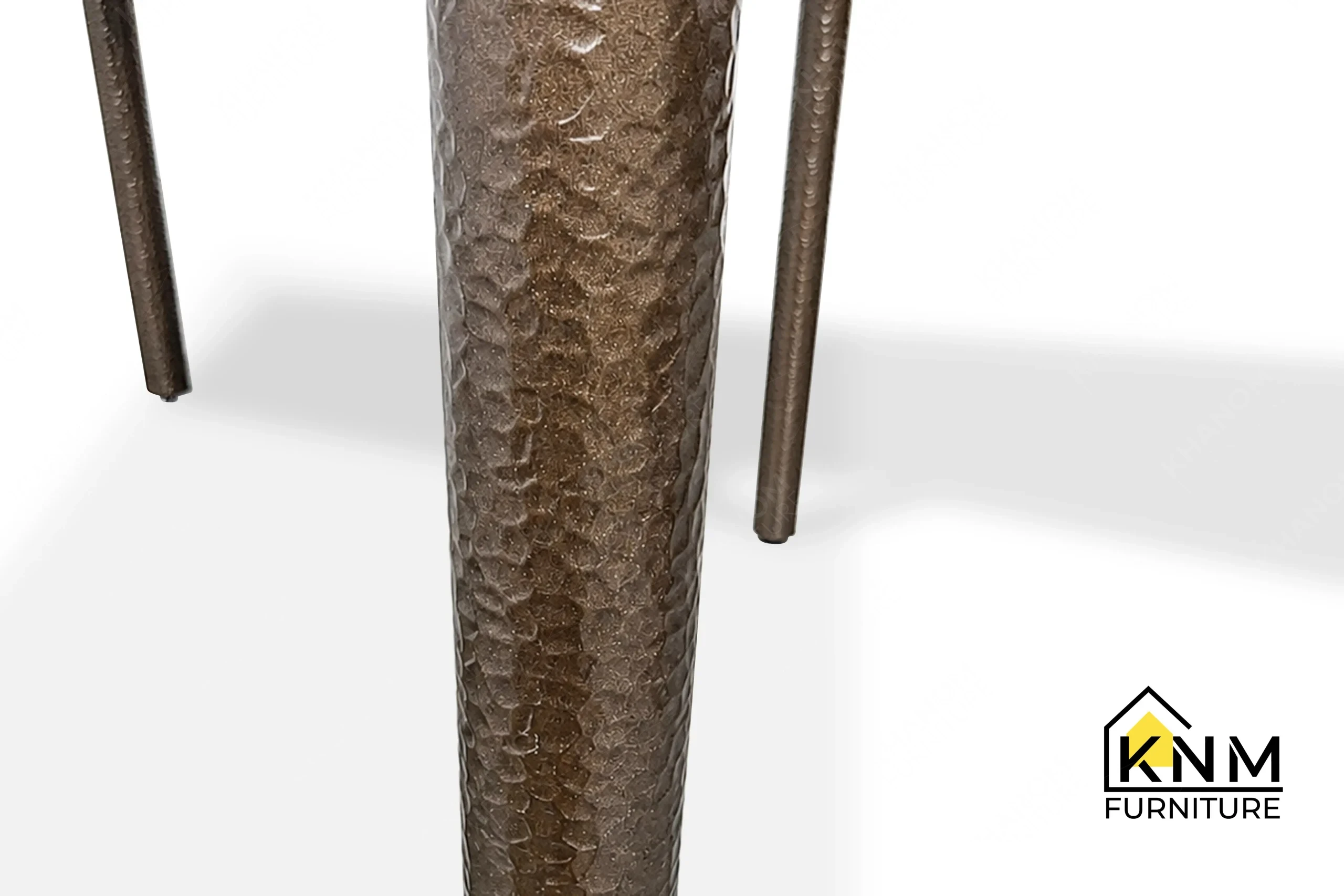 A technical detail of the 4-top stone rectangular dining table from Khanom Furniture, describing the Hammered Bronze texture on the metal legs.