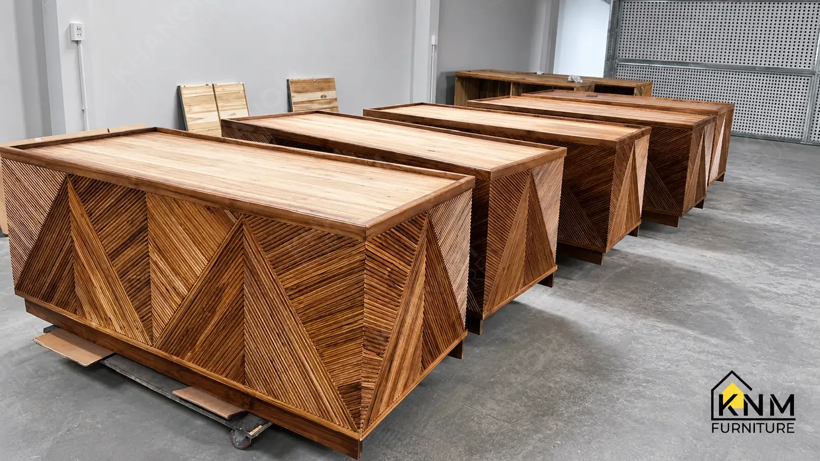 Five identical finished solid wood bar counter units with diagonal reed-panel decorative detail staged side-by-side for pre-shipment quality inspection at Khanom Furniture (KNM Furniture) Vietnam.