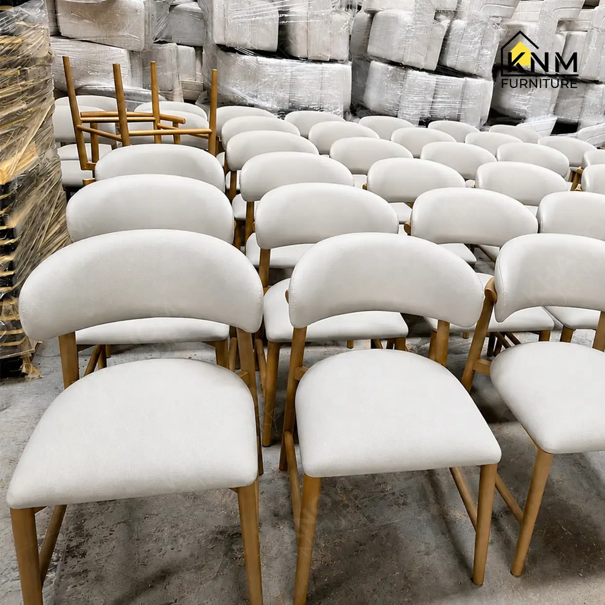 Rows of finished cream upholstered dining chairs with gold metal frames staged for pre-shipment quality inspection at Khanom Furniture (KNM Furniture), Vietnam