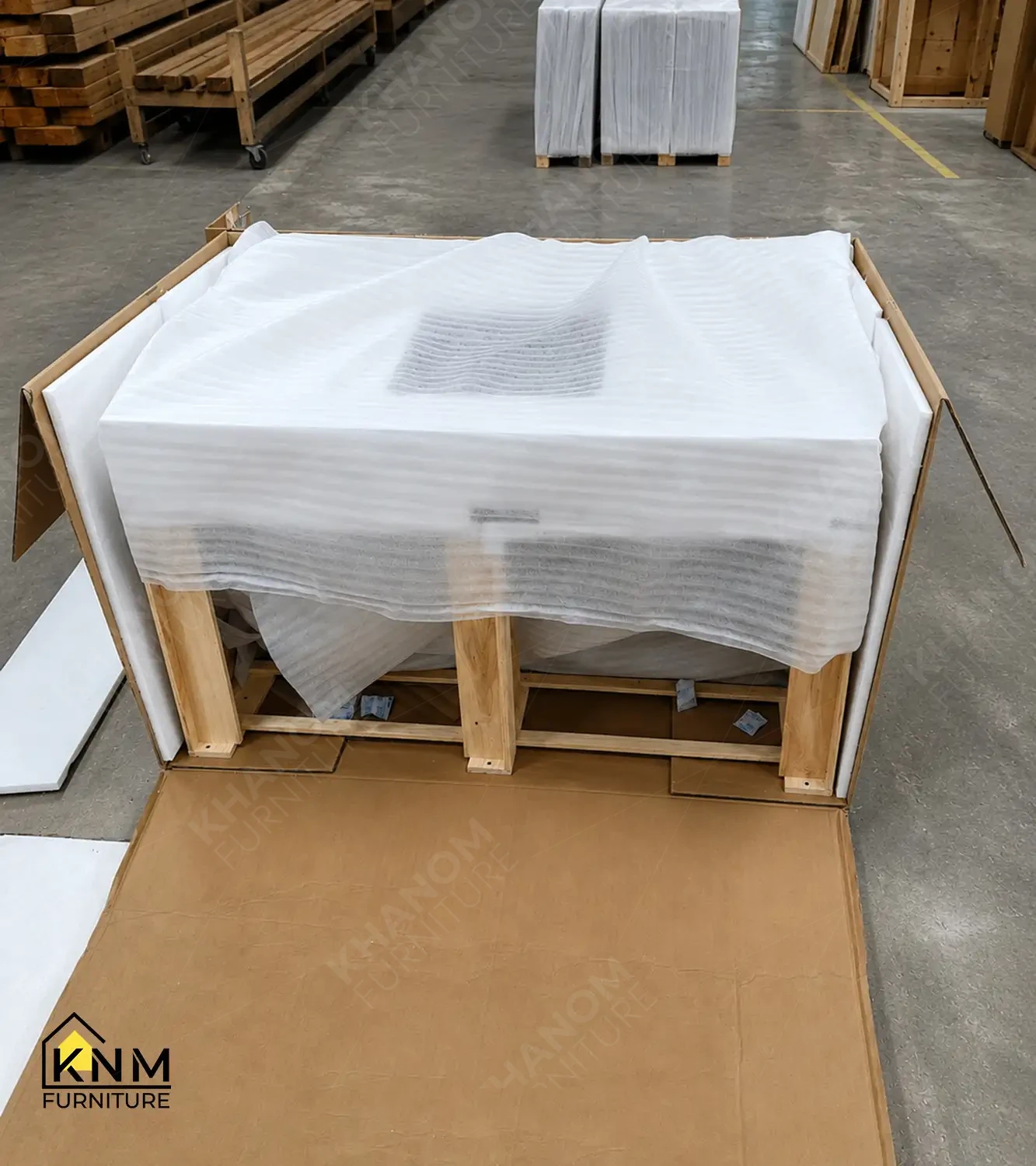 Interior of an opened Khanom Furniture (KNM Furniture) wooden export crate showing furniture piece wrapped in white EPE foam cushioning positioned inside a wooden structural cradle, packaging layers visible.
