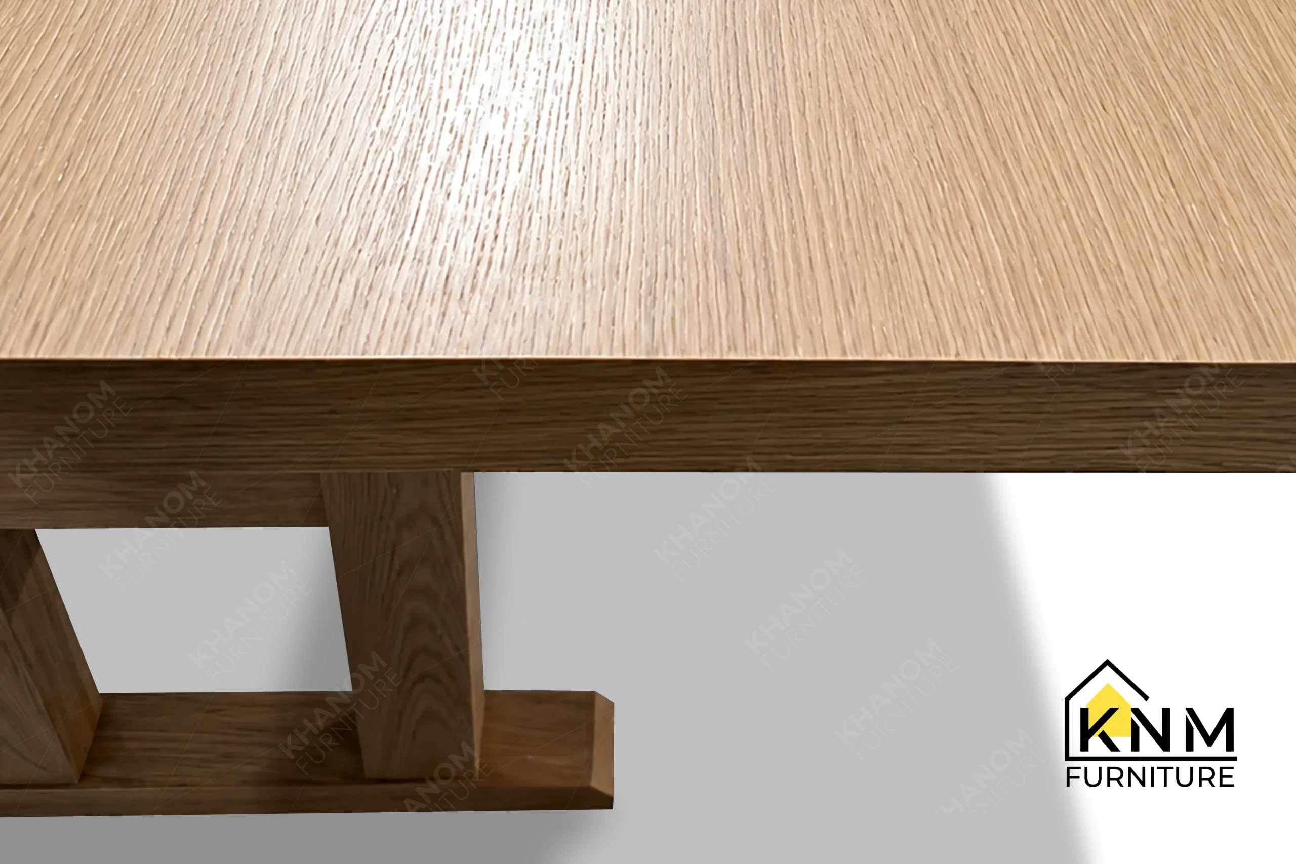 A detailed material zoom of the 120-inch solid oak communal table by Khanom Furniture, showing the natural grain of the oak veneer.