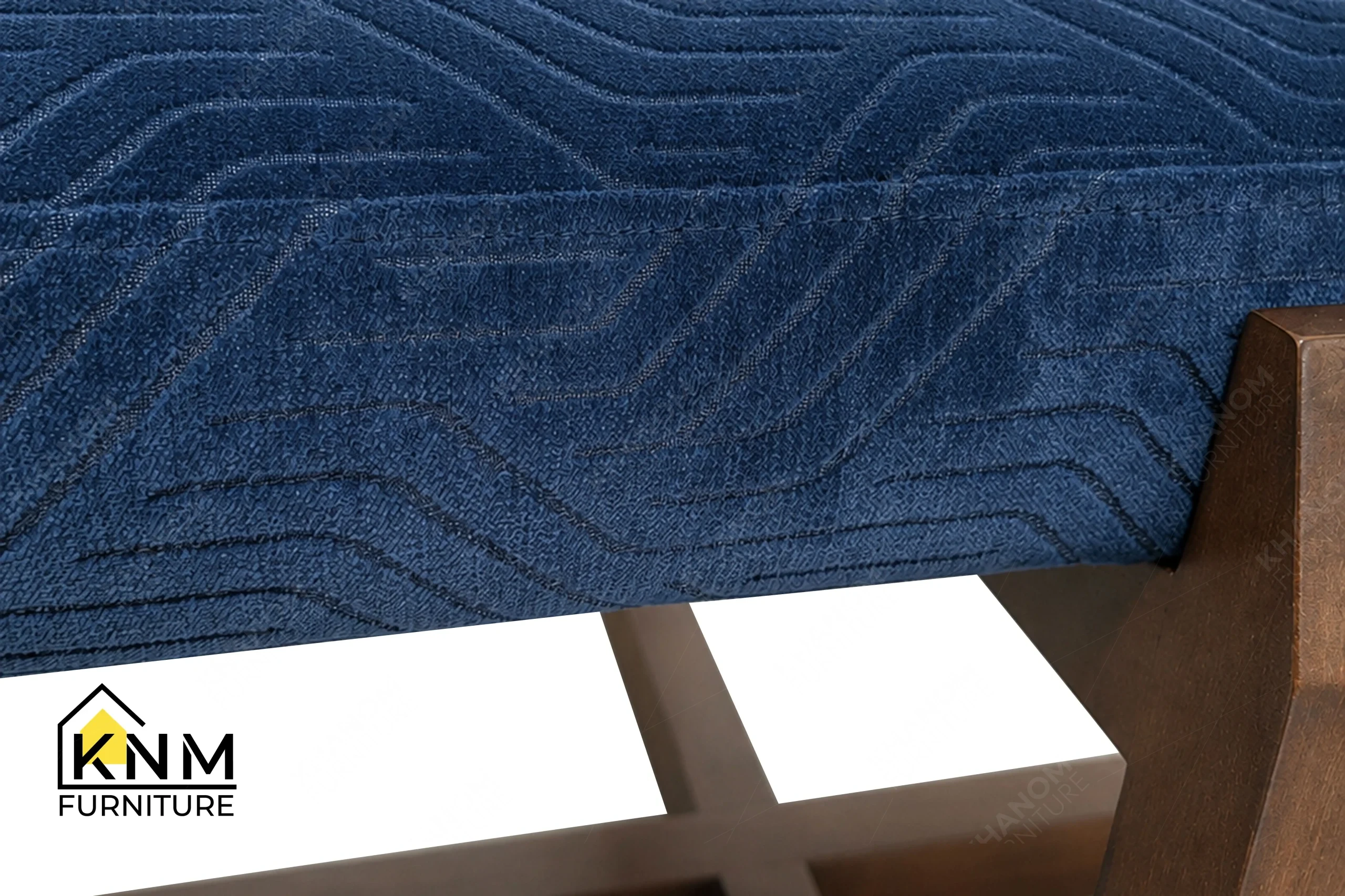 A detailed material zoom of the Fabricut upholstered solid Beech dining bench by Khanom Furniture, showing the texture of the Doubletake Prussian fabric.