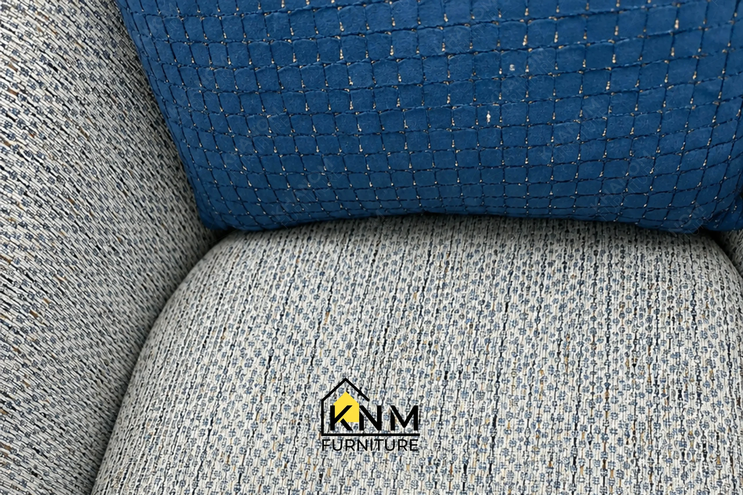 A detailed material zoom of the Fabricut upholstered swivel lounge chair by Khanom Furniture, showing the contrast between the textured body and sapphire pillow.