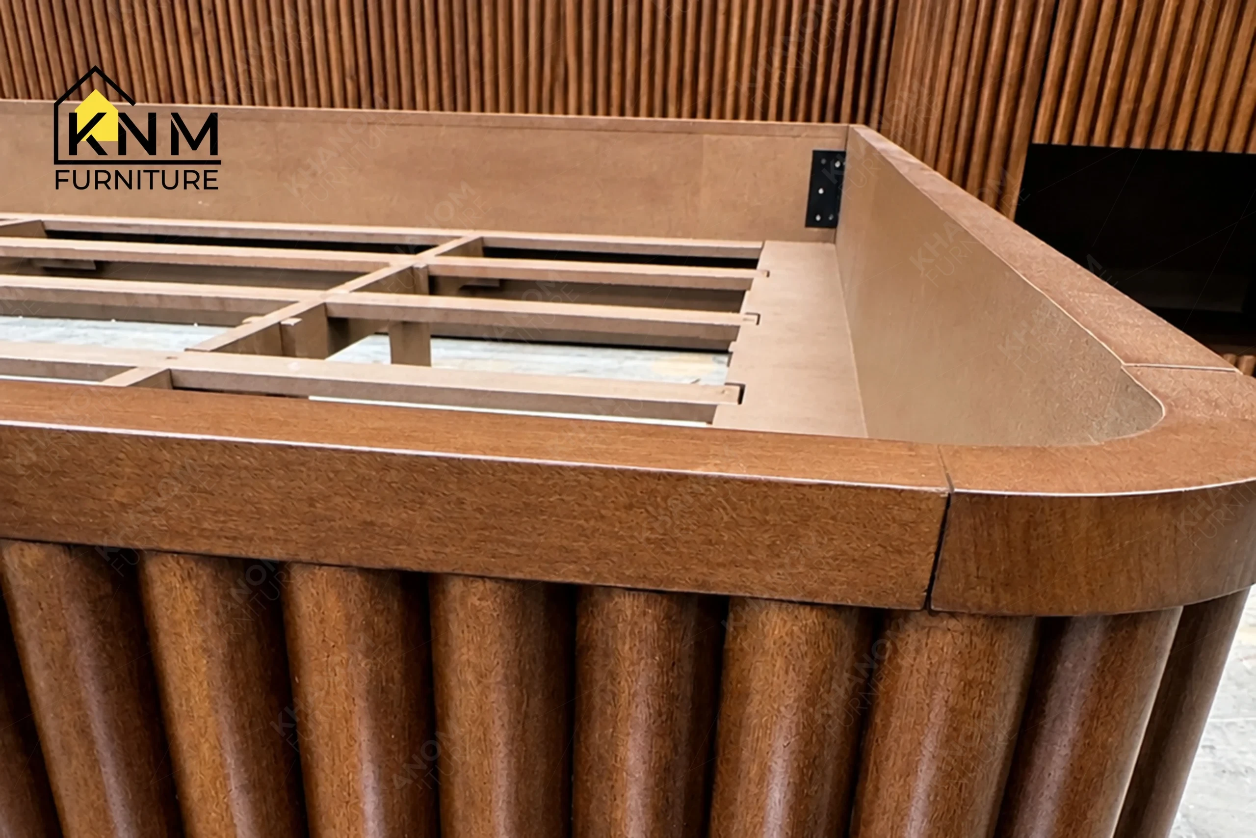 A detailed material zoom of the fluted hardwood King bed system by Khanom Furniture, showing the engineered 1.5mm V-grooves between the wood panels.