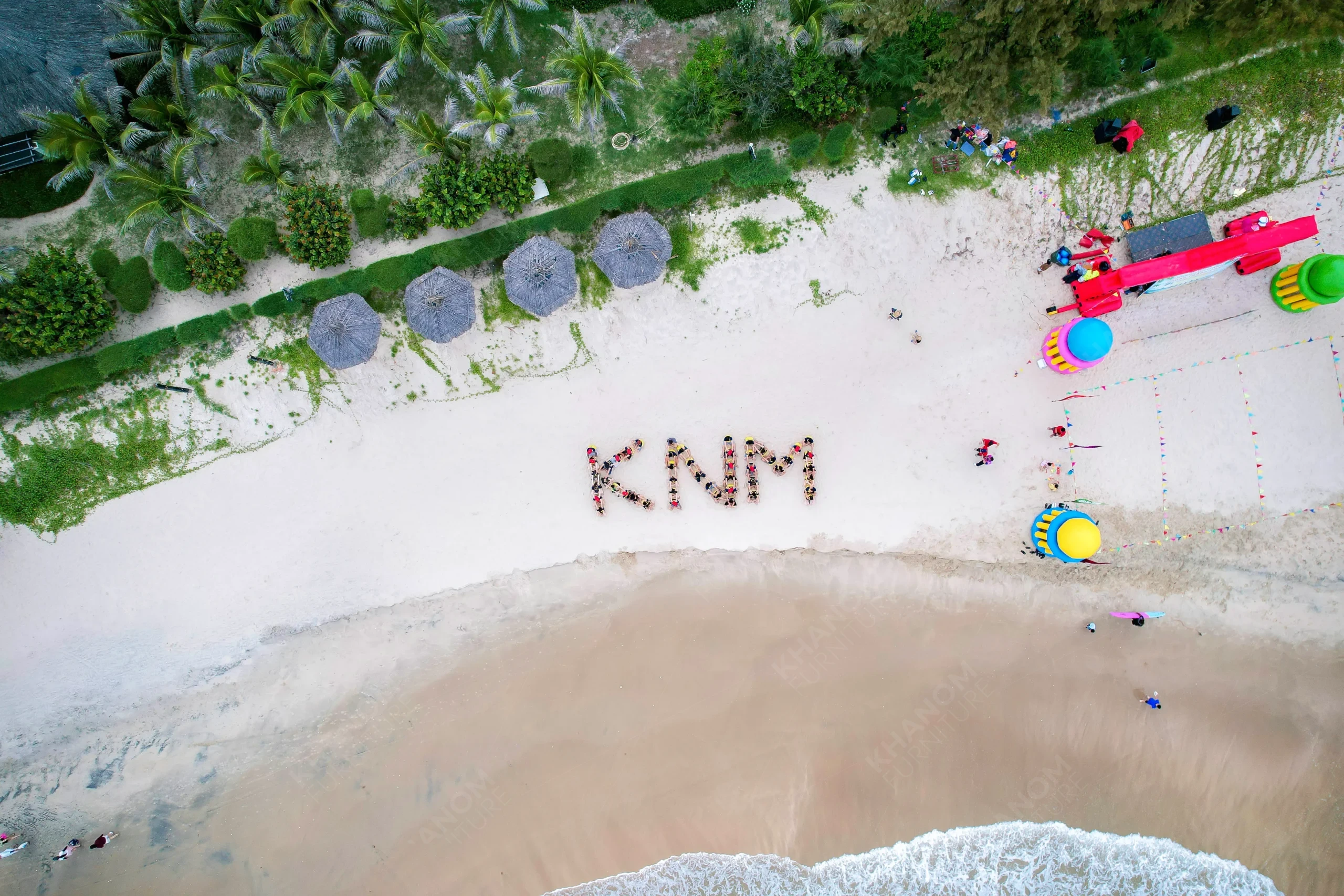 Wide aerial view of KNM Furniture team spelling "KNM" on Phan Thiết beach