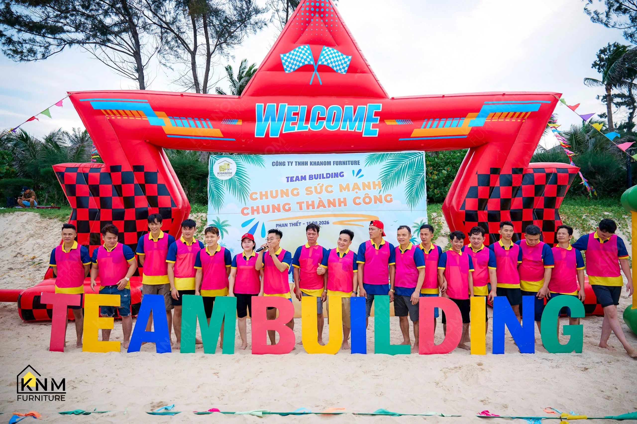 KNM Furniture team members in pink vests at Welcome Arch, team building 2026